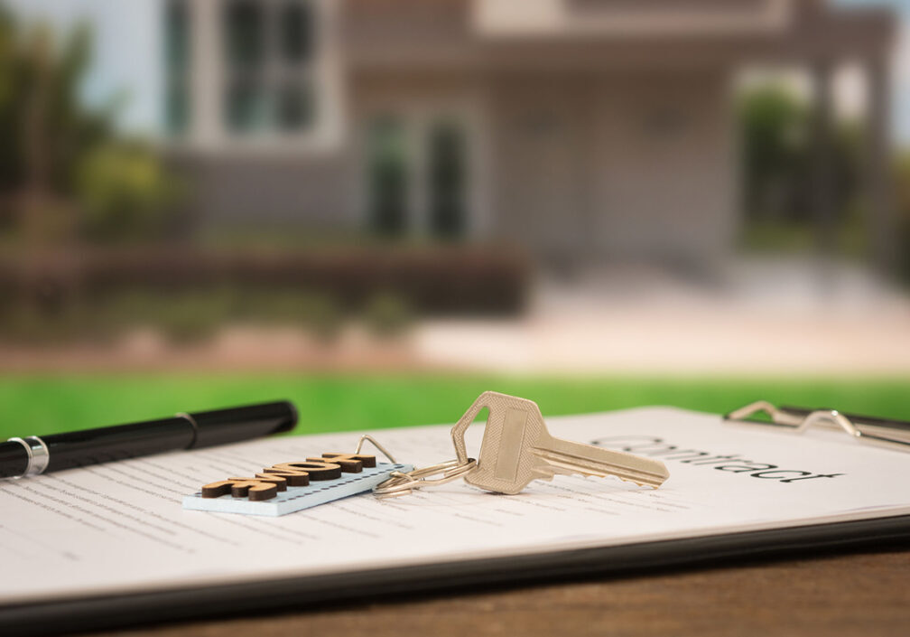 house keys closeup house key on contract document with house key in house background.
